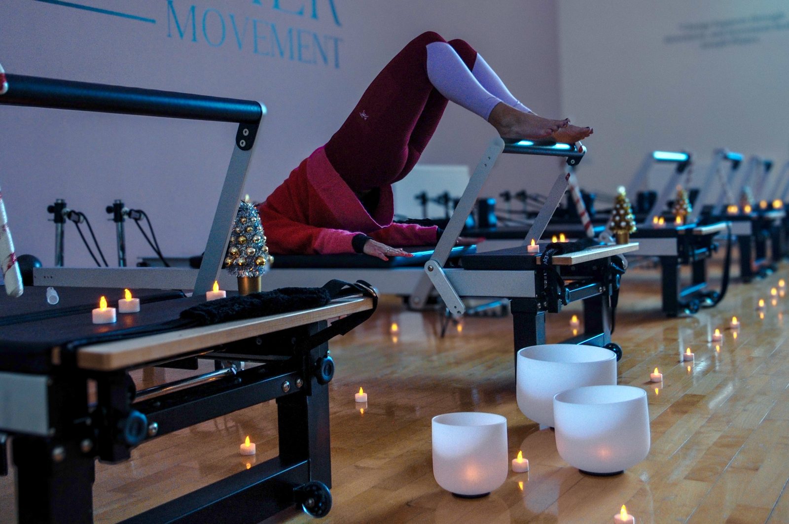 A row of reformer beds lit by candles and singing bowls